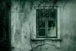 A creepy woman in the window of a haunted house.