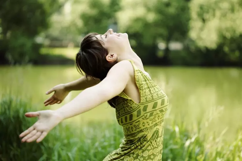 happy young woman with arms thrown out in green field in the Smoky Mountains