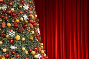 A_Christmas_tree_on_stage_in_front_of_a_red_curtain