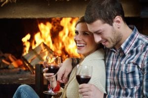 couple drinking wine in front of the fire