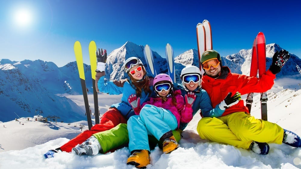 Family sitting in snow while skiing in mountains