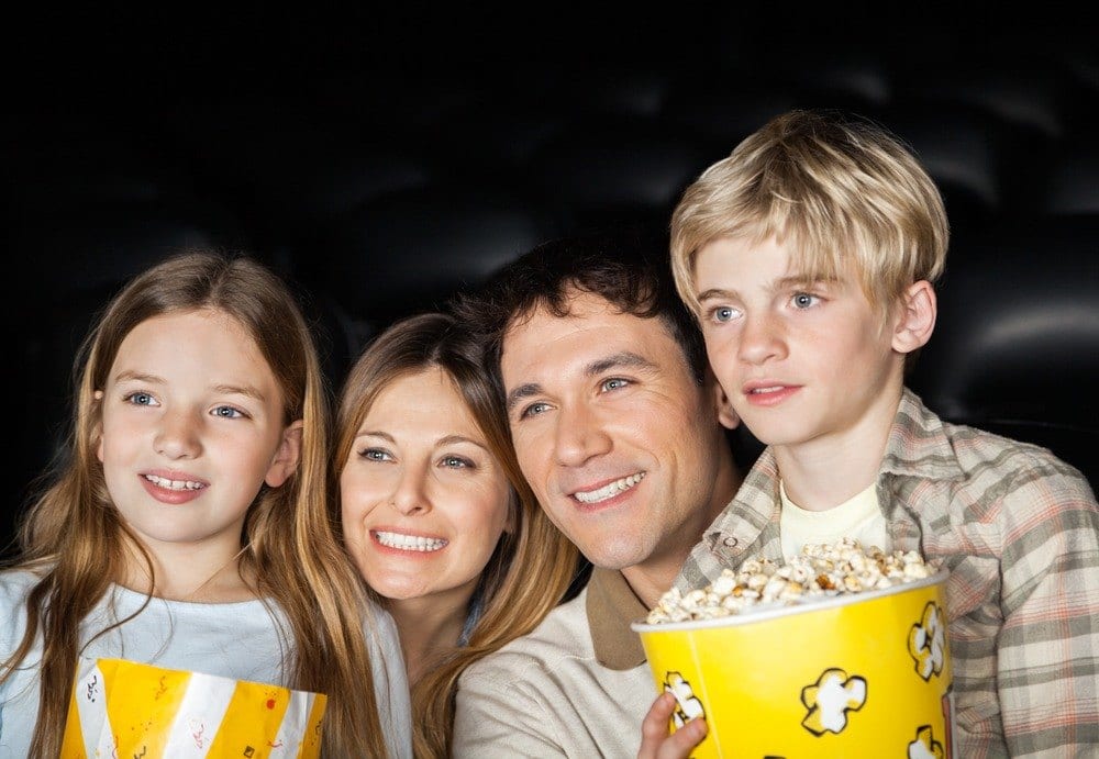Family watching a movie with popcorn at a Gatlinburg cabin with theater room