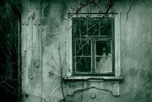 A creepy woman in the window of a haunted house.
