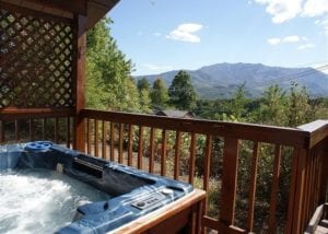 A hot tub on the deck of a cabin with beautiful mountain views.