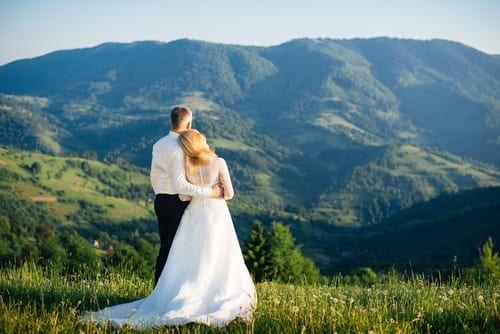 Bride and groom standing on hillside gazing at the majestic Smoky Mountains