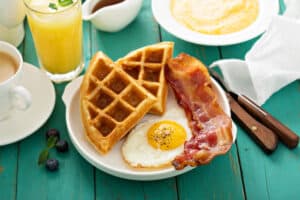 plate full of waffles, bacon, and eggs